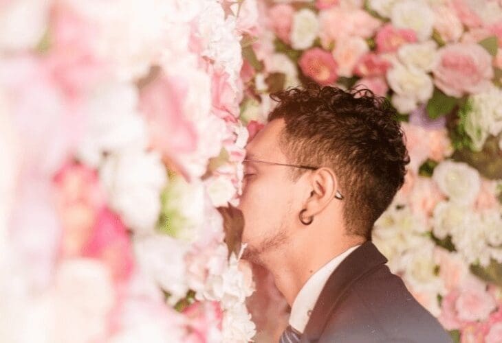 En mann dytter ansiktet inn i en vegg av rosa blomster