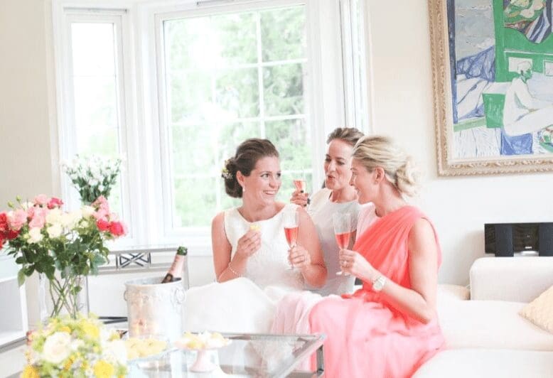 To jenter og en hvit brud drikker Prosecco og forbereder seg til bryllup