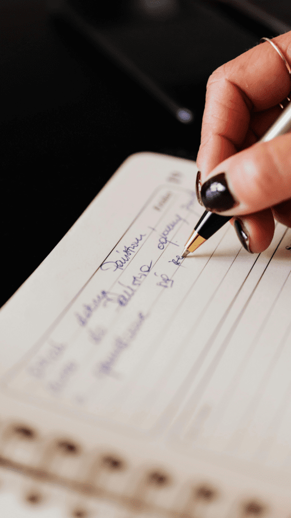 Nærbilde av skrivebok og penn i hånden som brukes til å planlegge tidsskjema for bryllupsdagen