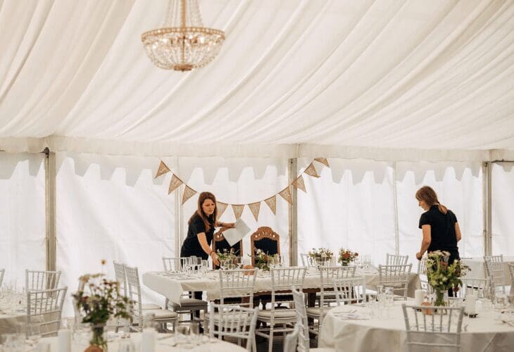 Catering firma dekker opp bord til bryllup i et partytelt