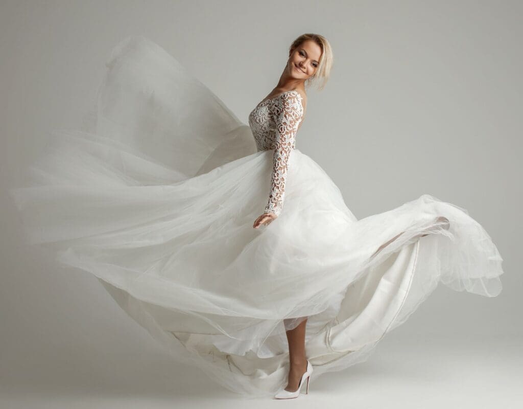 En brud, sett fra siden sparker en fot bakover slik at kjolen flyr litt i luften. Representerer brudekjoleprøving. Vi kommer med tipsene du trenger.