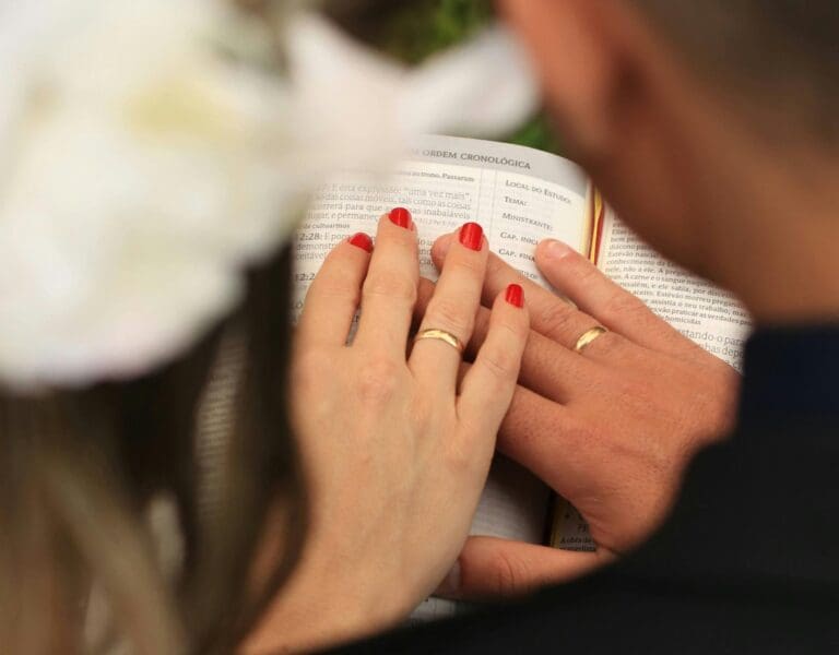 Et brudepar holder hendene på en salmebok for å velge salmer i bryllup