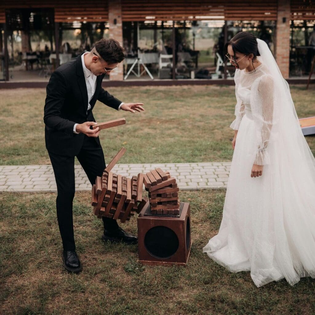 Et brudepar spiller kjempejenga under bryllupsleker