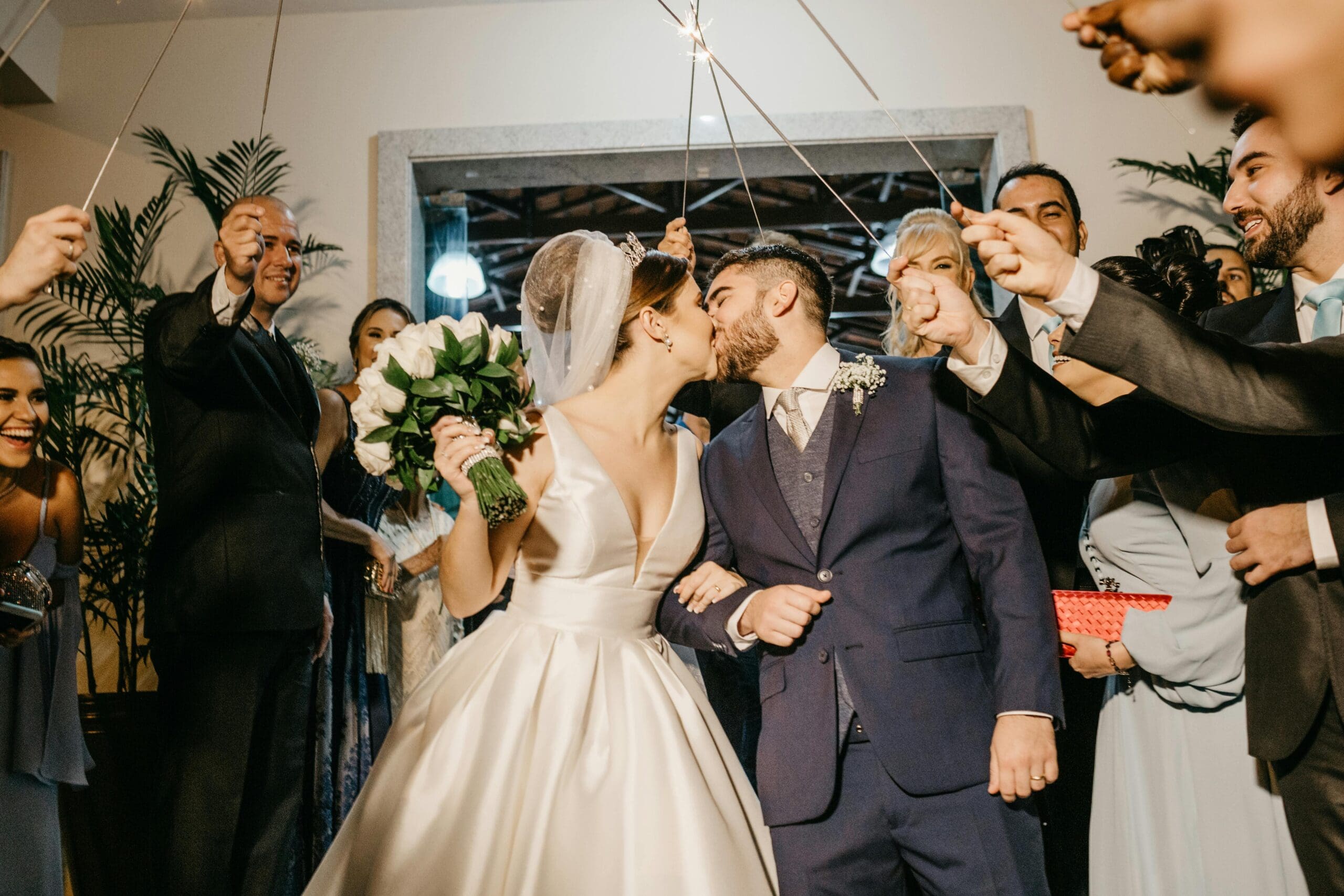 Brudepar kysser lykkelig midt i rommet mens gjester med stjerneskudd står rundt dem under bryllupsfestens mottakelse