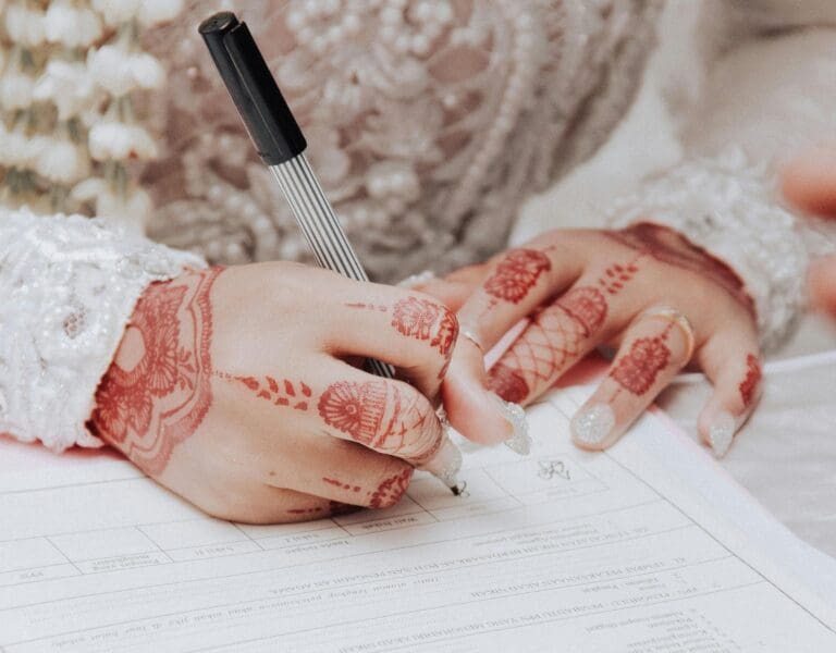 En indisk brud med hennatatoverte hender skriver under juridiske dokumenter