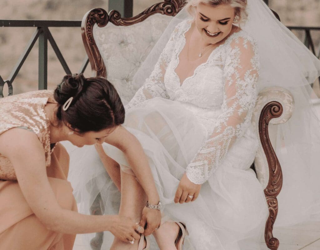 Brud får hjelp med å ta på seg skoene mens hun klargjøres til bryllupet, illustrerende viktigheten av en effektiv kjøreplan for bryllupsdagen