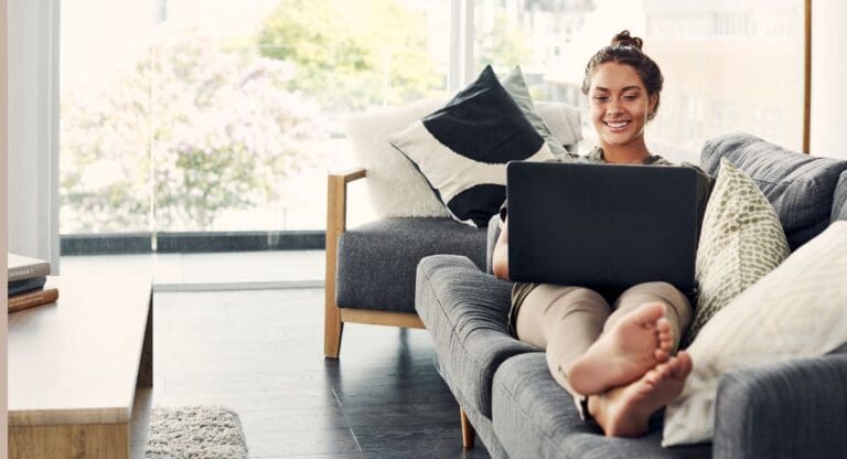 Kvinne ligger på en sofa med en laptop i fanget og planlegger bryllupet sitt med Bryllupshjelperens digitale bryllupsplanlegger og bryllupsplattform