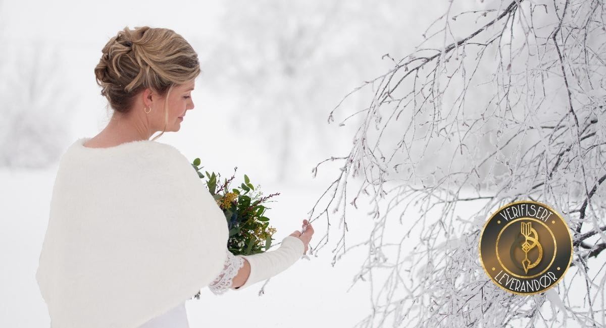 En brud i hvit cape fra Brudedrøm tar på en kvist dekket av frost