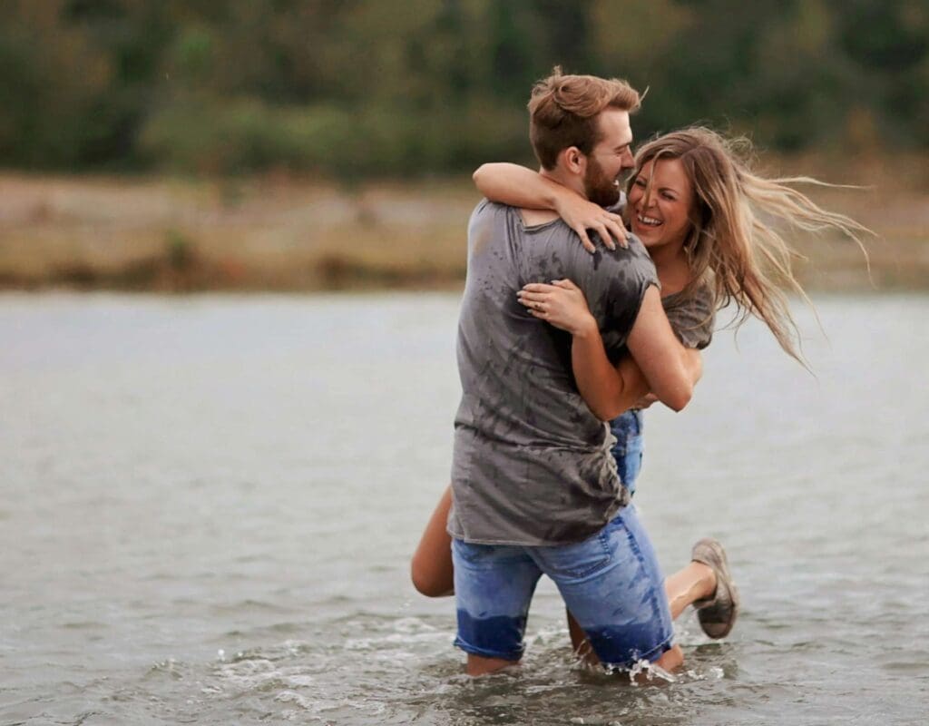 Et par leker og ler sammen i vannet, feirer bryllupsdag med glede. Mannen står med ryggen til, vendt mot kvinnen, som en symbolsk markering av et langt og lykkelig ekteskap