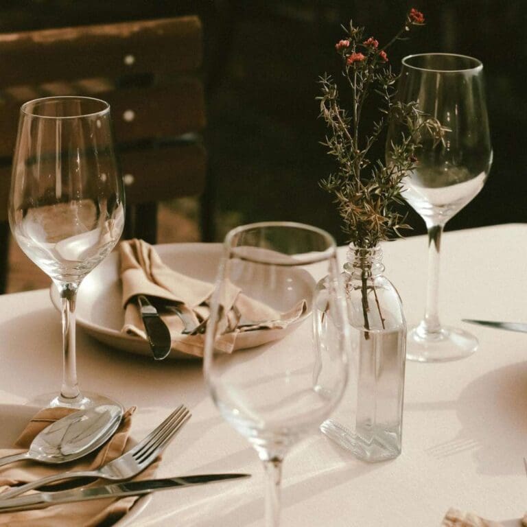 enkel men pen bordsetting, en enkel vase med en blomst, fire tallerkener med glass og bestikk, og enkel linserviett. Enkelt oppsett kan også være pent og budsjettvennlig.