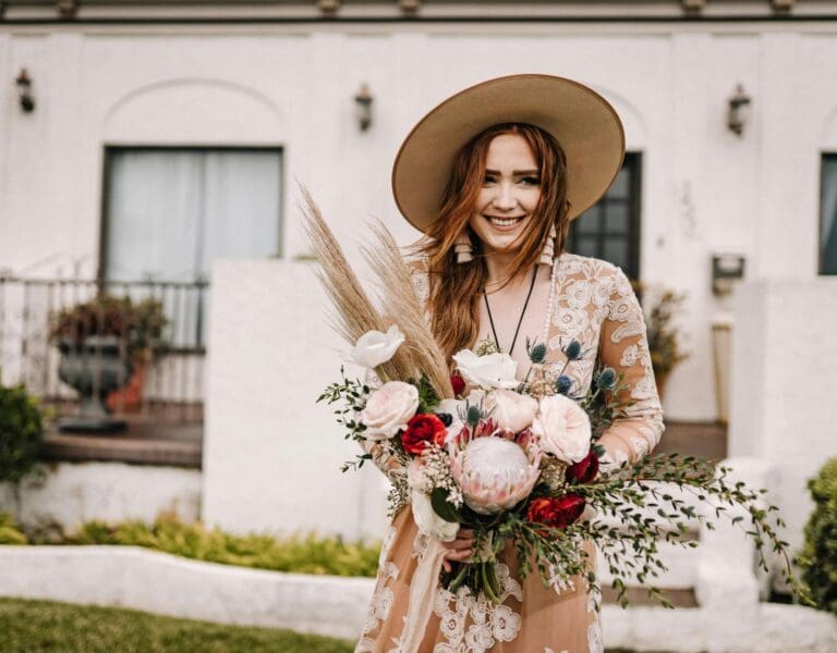 En rødhåret bohemsk brud med hatt og blomster