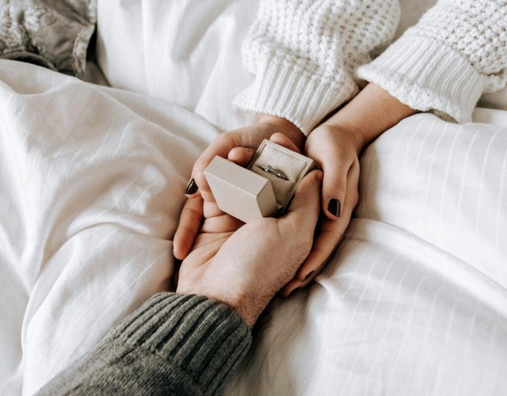 to hender som holder en forlovelsesring i en eske, han har fridd og hun tar imot. romantisk bilde