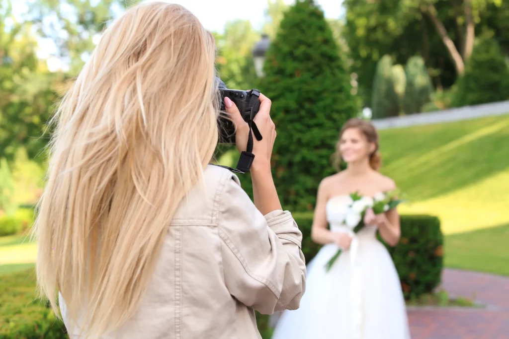 Photographer taking photo of beautiful bride outdoors