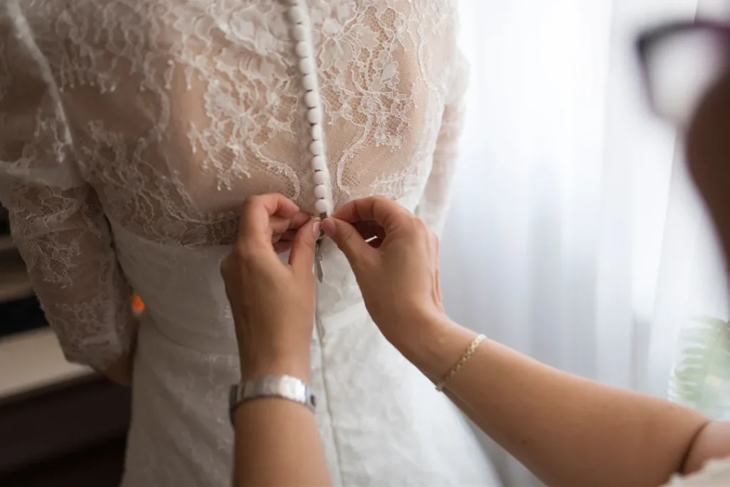 Detalj av brudekjole med transparente blomsterblonder og knapper i ryggen