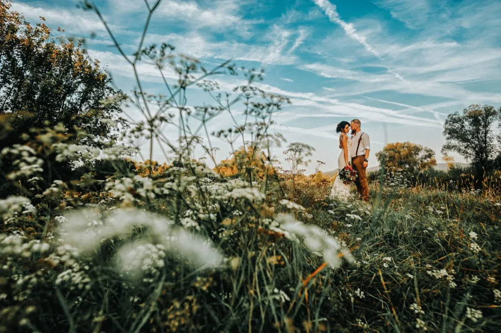Brudepar sammen i en eng med ville blomster og naturlige omgivelser