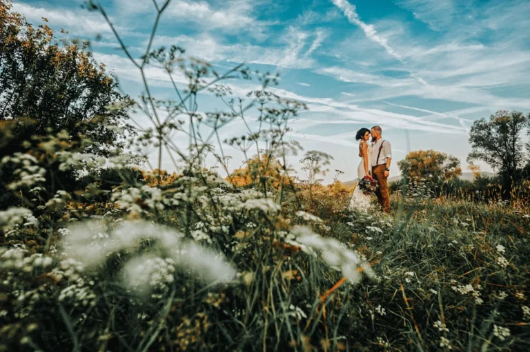 Brudepar sammen i en eng med ville blomster og naturlige omgivelser